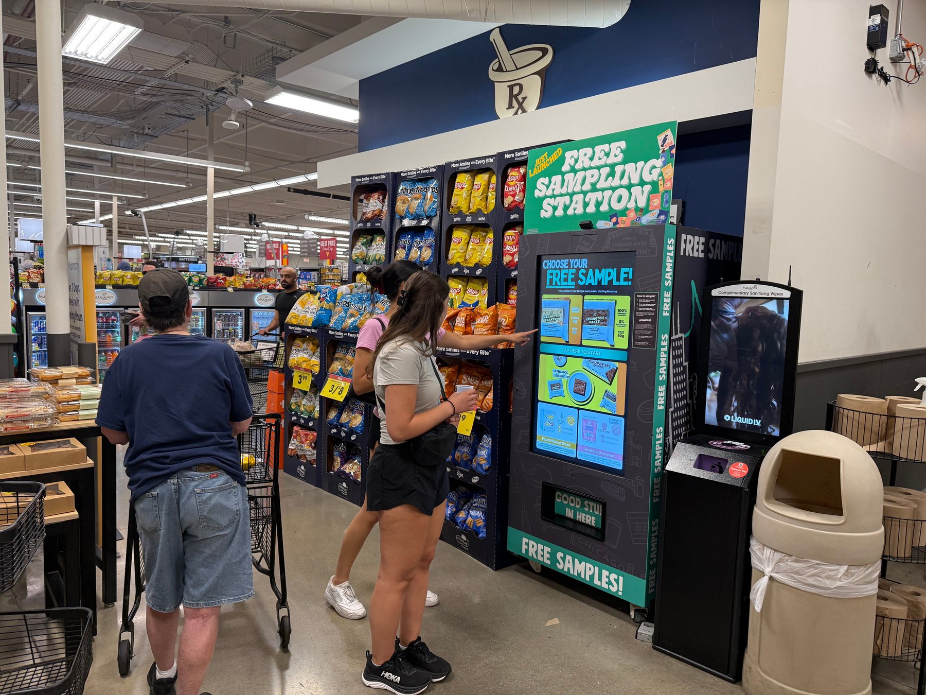 A Showdrop sampling kiosk at the front of a Mariano’s store, with shoppers trying samples